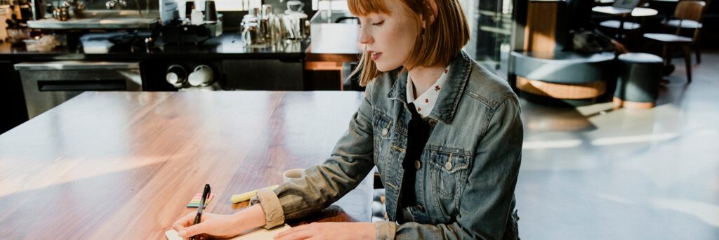 Woman writing on her notebook in a cafe